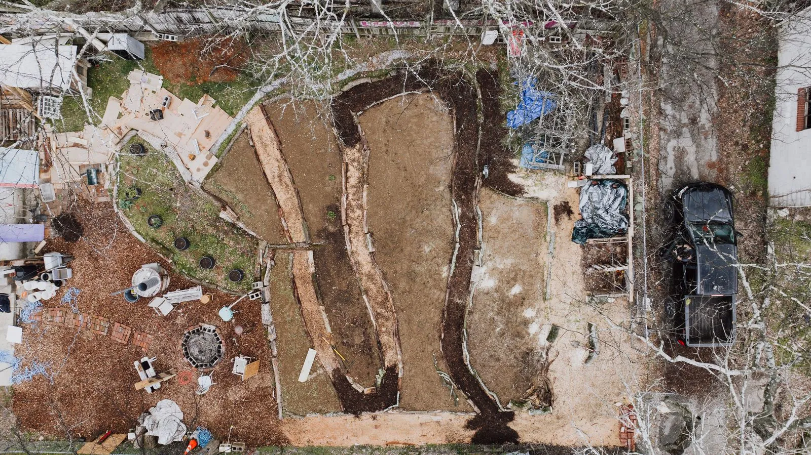 Aerial shot of a backyard construction site with various materials and earthworks.